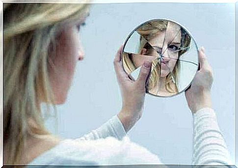 A teenage girl looking at herself in a broken mirror.