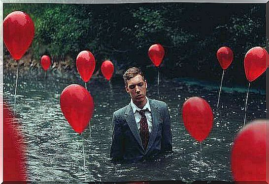 Man standing in deep water with balloons