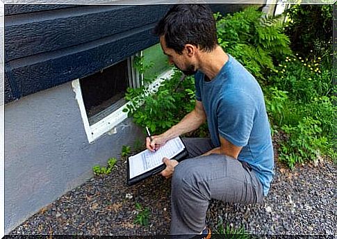 man bent down and took notes on a clipboard about the shape of the house