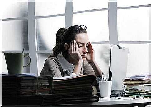 Woman with stress headache in front of a computer at work