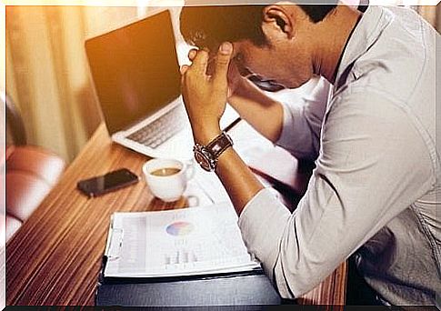 Young man with headache at his desk in an office